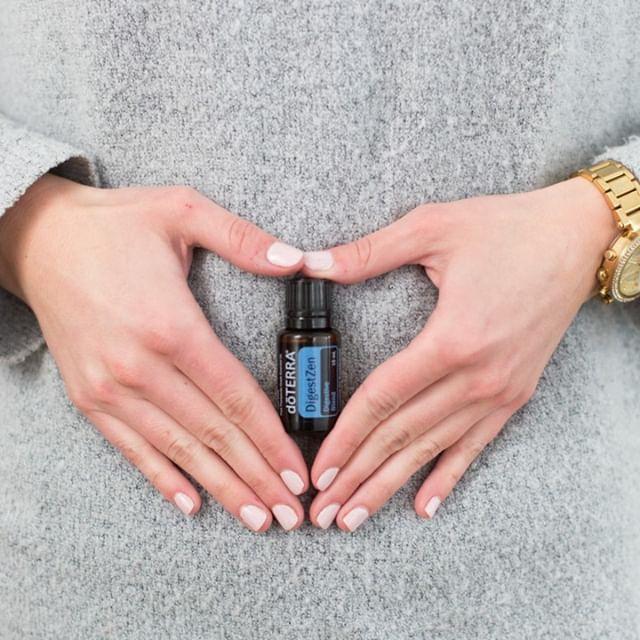 Una botella de aceite esencial doTERRA está en manos de una mujer que la sostiene contra su estómago.