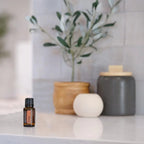 Aceite esencial de clavo dōTERRA 15 ml en encimera junto a difusor aromático blanco y plantas decorativas