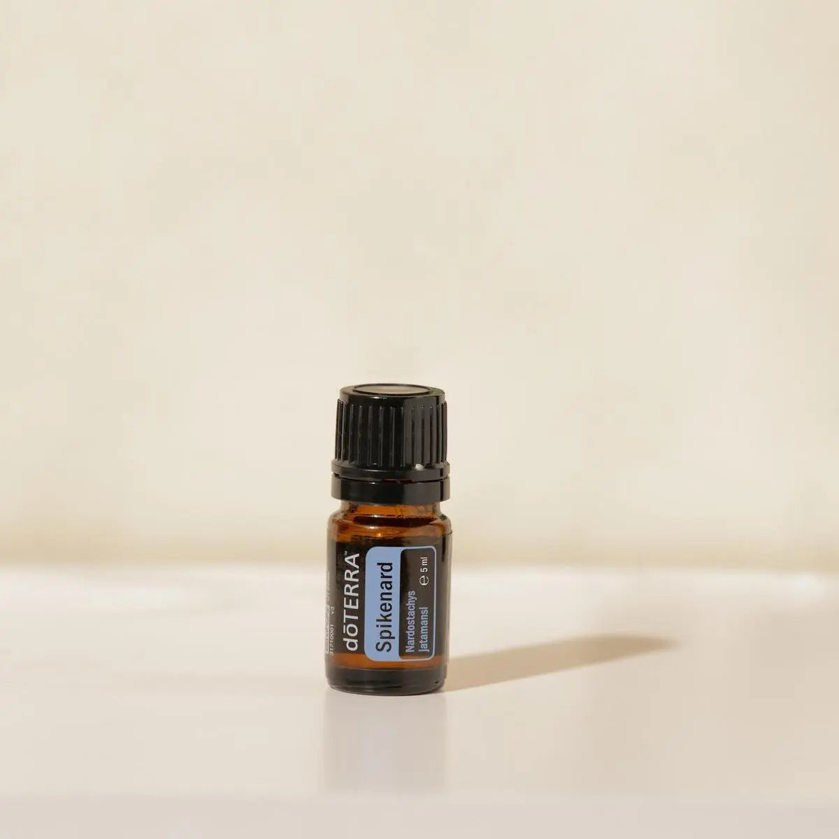 Aceite Esencial Espicanardo dōTERRA 5ml sobre superficie crema minimalista con sombra suave