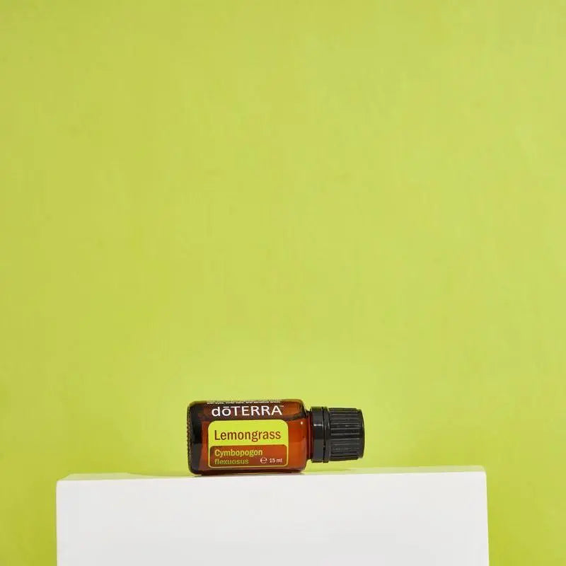 Frasco de aceite esencial de Lemongrass doTERRA 15ml sobre pedestal blanco con fondo verde lima chartreuse de estudio