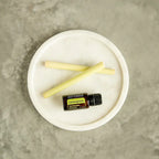 Aceite esencial de Lemongrass doTERRA 15ml sobre plato de marmol blanco junto a dos tallos frescos de hierba limon pelados