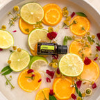 Aceite Esencial Lima dōTERRA 15ml en cuenco con rodajas de lima y naranja con flores cenital
