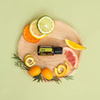 Aceite Esencial Lima dōTERRA 15ml en tabla de madera con cítricos variados y romero sobre fondo verde