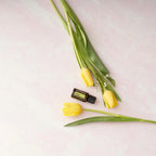 Aceite Esencial Lima dōTERRA 15ml con tulipanes amarillos sobre mármol rosa vista cenital