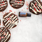 Aceite esencial Peppermint dōTERRA 15ml entre galletas de chocolate, candy cane y glaseado blanco sobre mármol