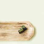 Aceite esencial de Orégano dōTERRA 15ml en bandeja alargada de madera rústica con ramita de orégano fresco, fondo blanco