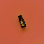 Aceite esencial de Oregano doTERRA 15ml en plano cenital sobre fondo terracota naranja