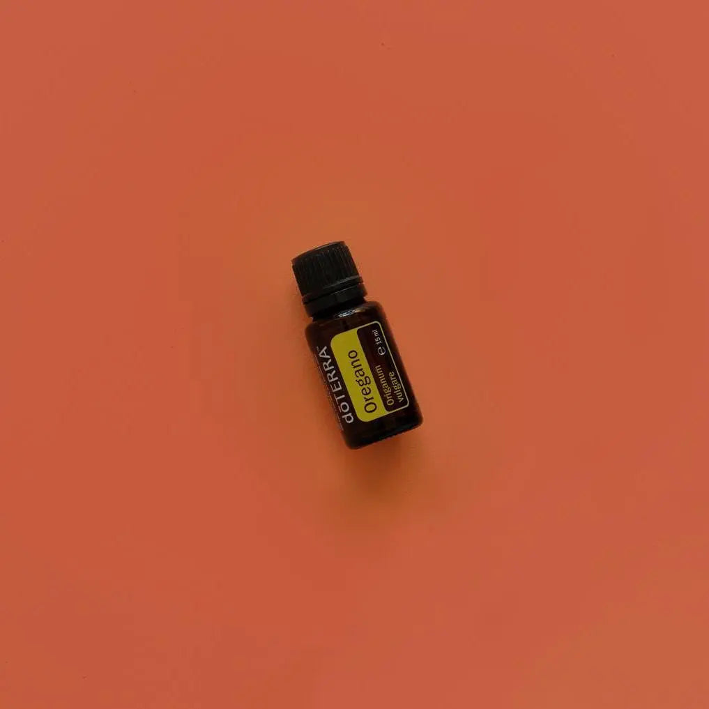 Aceite esencial de Oregano doTERRA 15ml en plano cenital sobre fondo terracota naranja