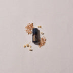Aceite esencial de Sándalo Indiano dōTERRA 5ml rodeado de astillas de madera de sándalo y flores blancas secas sobre fondo crema, vista cenital