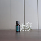 Aceite esencial Supermint dōTERRA 15ml — frasco en encimera gris pizarra con gypsophila y flores blancas