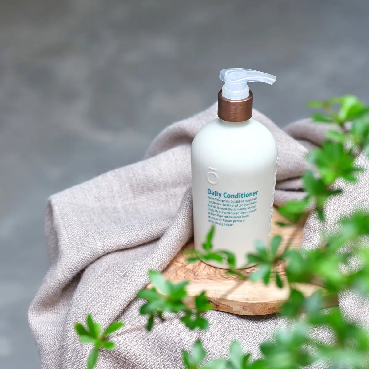Acondicionador Diario dōTERRA 500ml — frasco junto a plantas en encimera