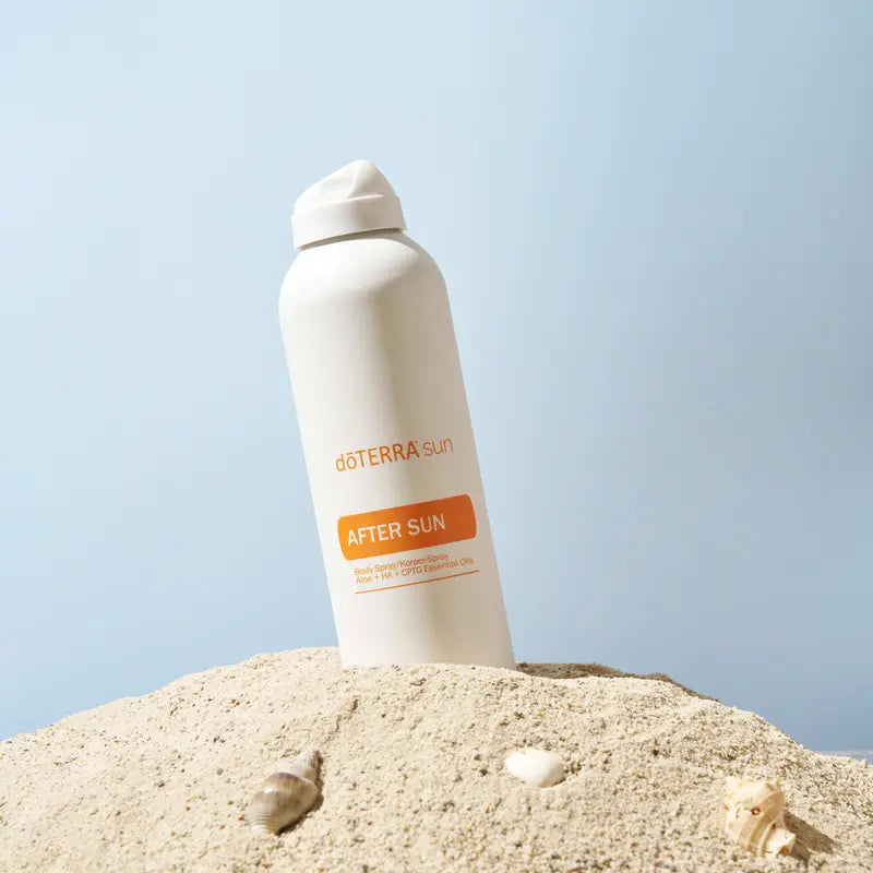 After Sun dōTERRA spray 170g — frasco en arena con conchas y fondo azul pastel