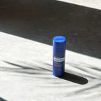 Barra Deep Blue Copaiba dōTERRA sobre superficie de piedra con sombras y luz solar
