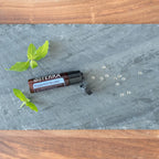Bolitas Menta Piperita Beadlets dōTERRA sobre pizarra gris con hojas de menta y perlas cenital