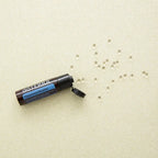 Peppermint Beadlets dōTERRA con perlas esparcidas sobre superficie dorada vista cenital