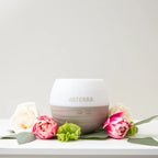Difusor Pétalo 2.0 dōTERRA rodeado de flores rosas y blancas sobre fondo claro
