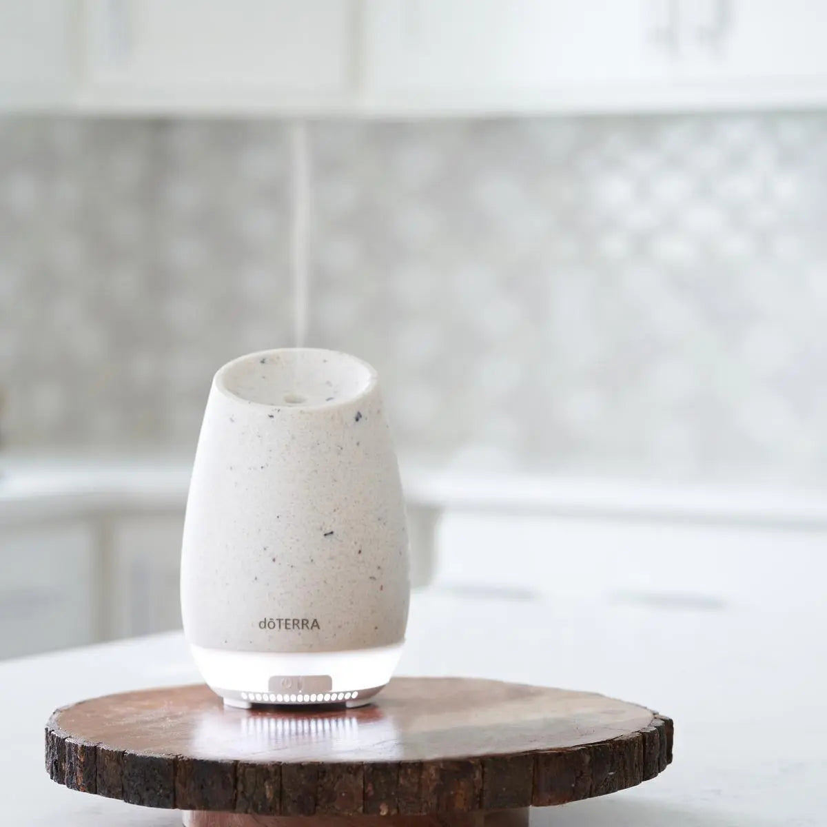 Difusor Roam dōTERRA sobre rebanada de madera en encimera de cocina con vapor