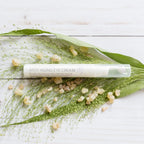 Envase de crema para el contorno de ojos dōTERRA Anti-Aging Eye Cream sobre hoja verde y resina de incienso en fondo de madera clara.
