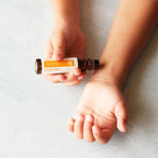 Niño sosteniendo el frasco roll-on dōTERRA Brave Touch de 10ml y aplicando la mezcla de aceites en la muñeca.
