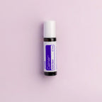 Frasco roll-on dōTERRA Calmer Touch 10ml centrado sobre fondo lila suave.
