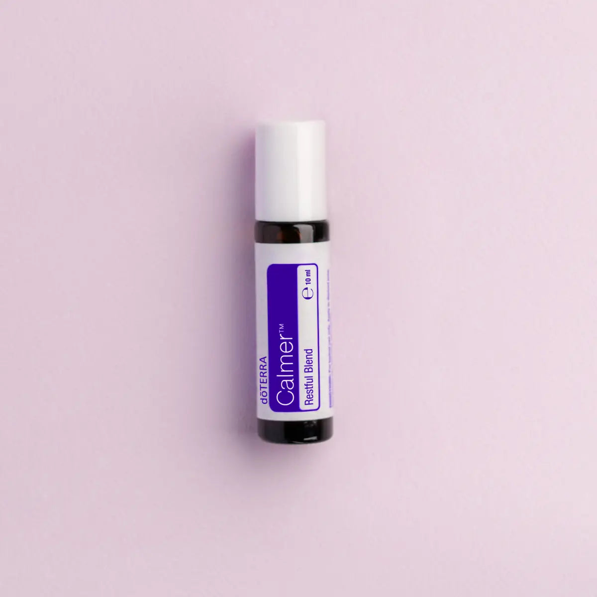 Frasco roll-on dōTERRA Calmer Touch 10ml centrado sobre fondo lila suave.