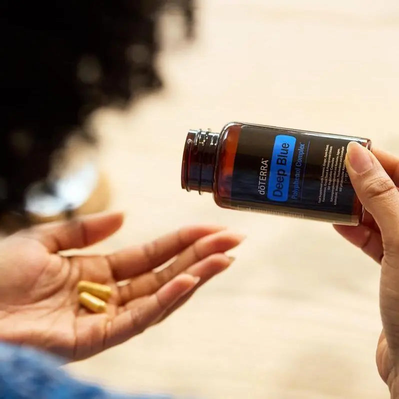 Mano recibiendo cápsulas doTERRA Deep Blue Polyphenol Complex vertidas desde el bote
