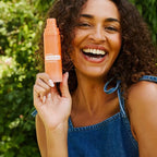 Mujer sonriendo con bruma doTERRA Endless Summer Hair & Body Mist 100 ml en jardín
