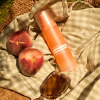 Bruma doTERRA Endless Summer Hair & Body Mist 100 ml con melocotones y gafas de sol en manta de picnic

