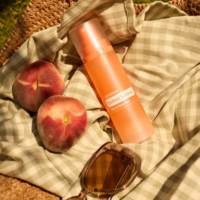 Bruma doTERRA Endless Summer Hair & Body Mist 100 ml con melocotones y gafas de sol en manta de picnic
