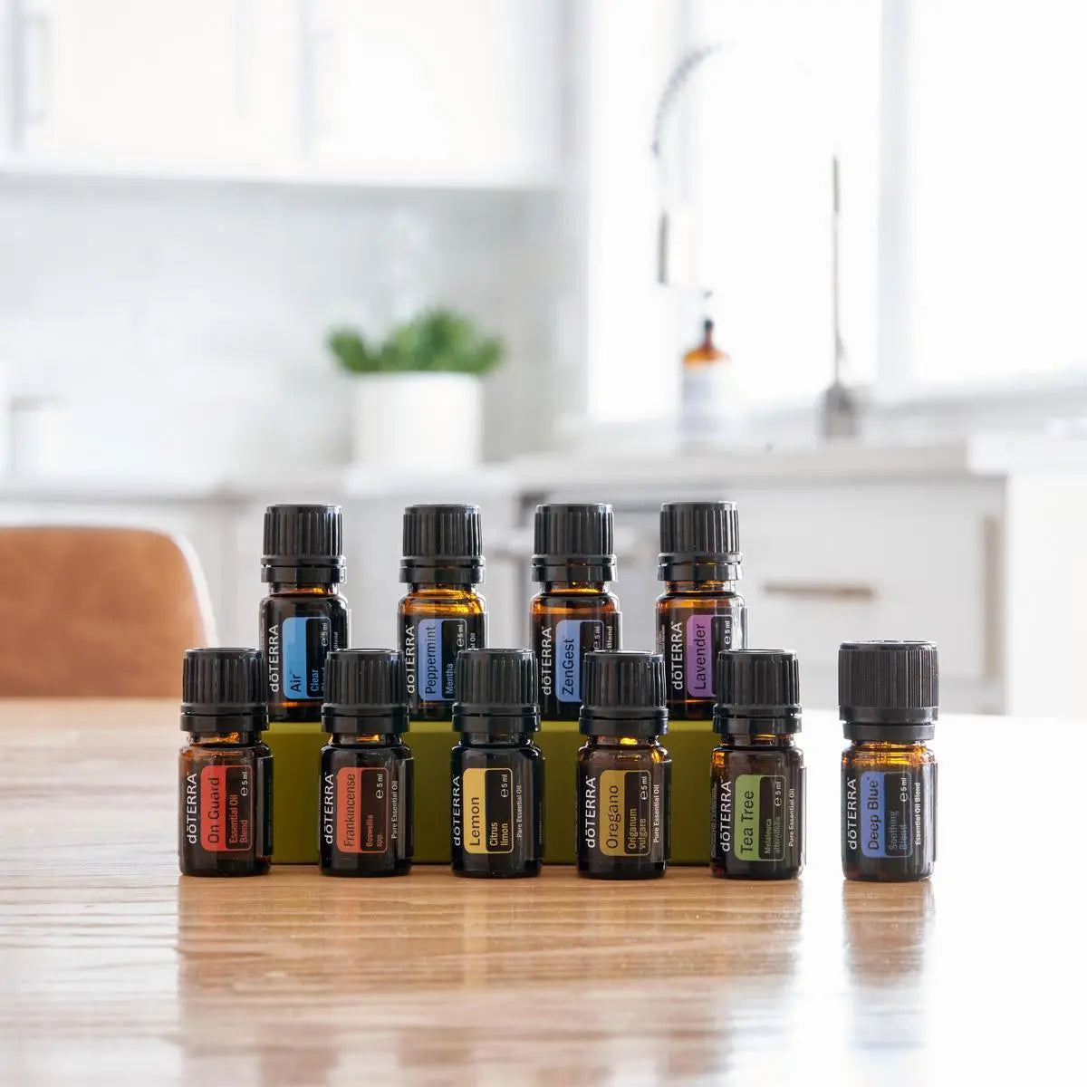 Conjunto de 10 frascos de 5ml del kit dōTERRA Family Essentials dispuestos en dos filas sobre mesa de madera.