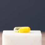 Detalle en primer plano de una cápsula de doble cámara dōTERRA Turmeric sobre bloque de mármol blanco