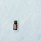 Frasco de aceite esencial dōTERRA ZenGest 15ml centrado sobre fondo de mármol azul claro.