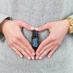 Frasco de dōTERRA ZenGest 15ml posicionado en el centro de manos formando un corazón sobre la zona abdominal.