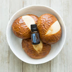 Vista superior del frasco de aceite esencial dōTERRA ZenGest 15ml sobre panes brioche en un cuenco blanco.