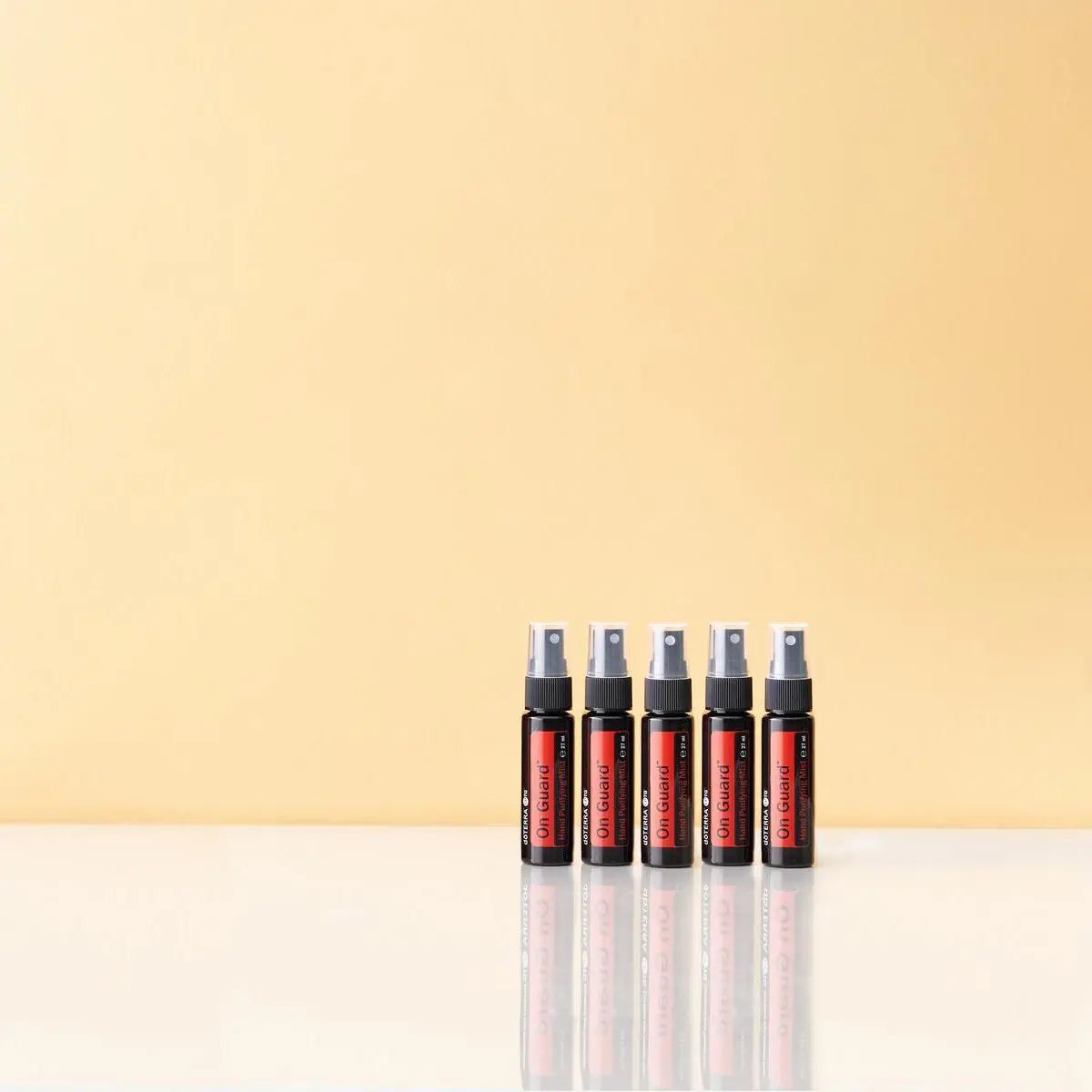 Espray purificador On Guard dōTERRA 27ml — cinco frascos en fila sobre fondo beige
