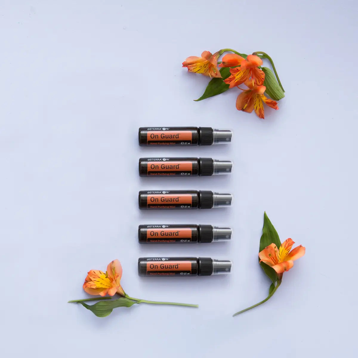 Espray purificador On Guard dōTERRA 27ml — pack de 5 en columna con flores naranjas