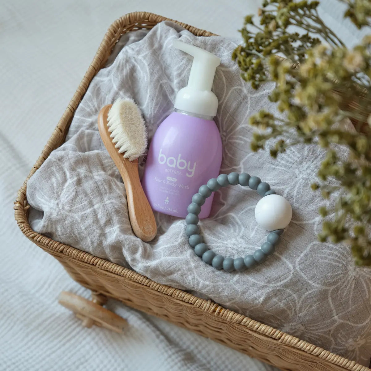 Espuma corporal y capilar para bebés dōTERRA — frasco junto a toalla fondo claro
