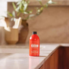Limpiador concentrado On Guard dōTERRA 237ml — frasco sobre mármol de cocina con plantas