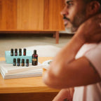 Kit AromaTouch Technique dōTERRA con caja de aceites sobre mesa de madera y hombre al fondo
