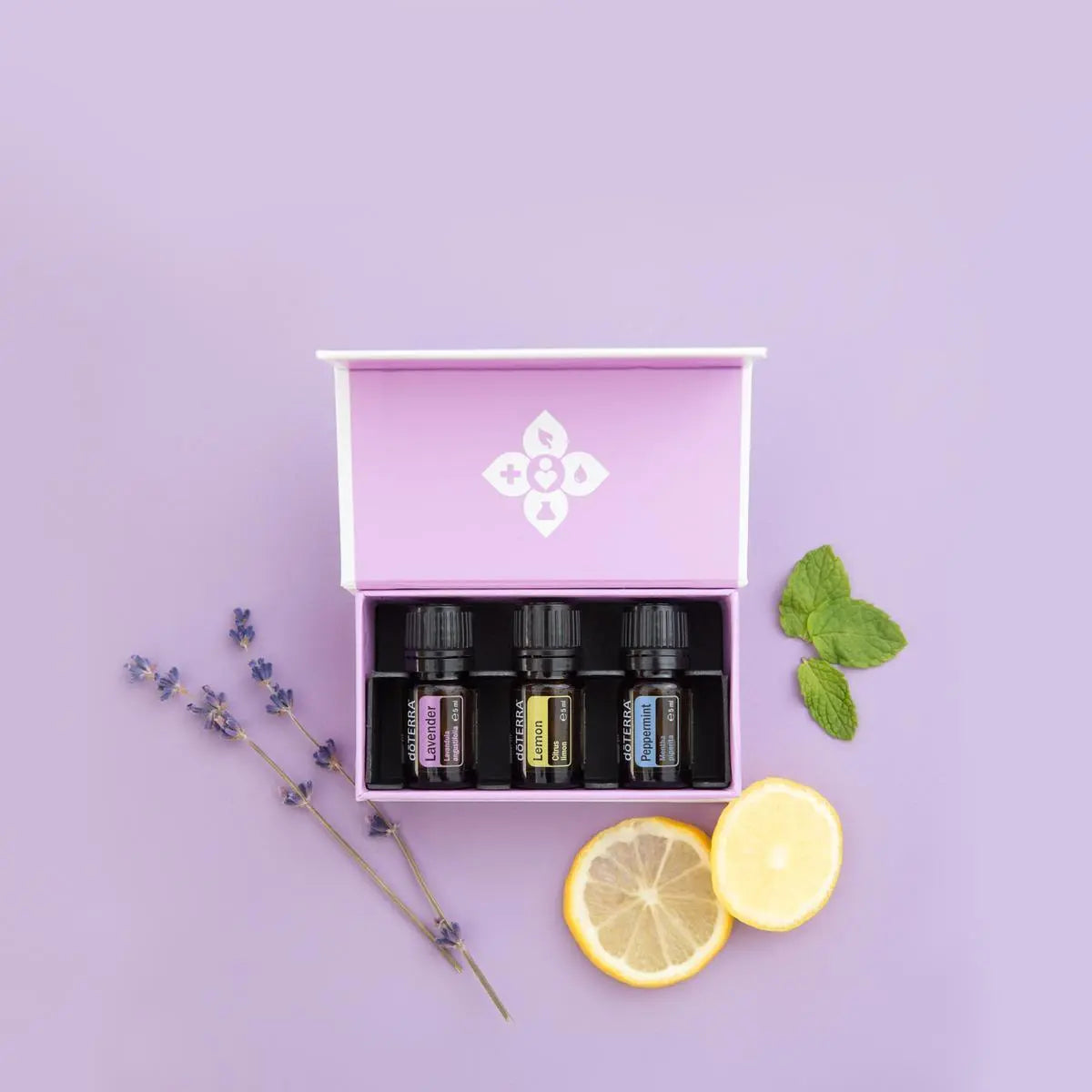 Kit introductorio dōTERRA EU — tres aceites esenciales sobre fondo púrpura en estudio