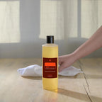 Limpiador concentrado On Guard™ dōTERRA 355ml con frasco sobre madera, mano y paño blanco