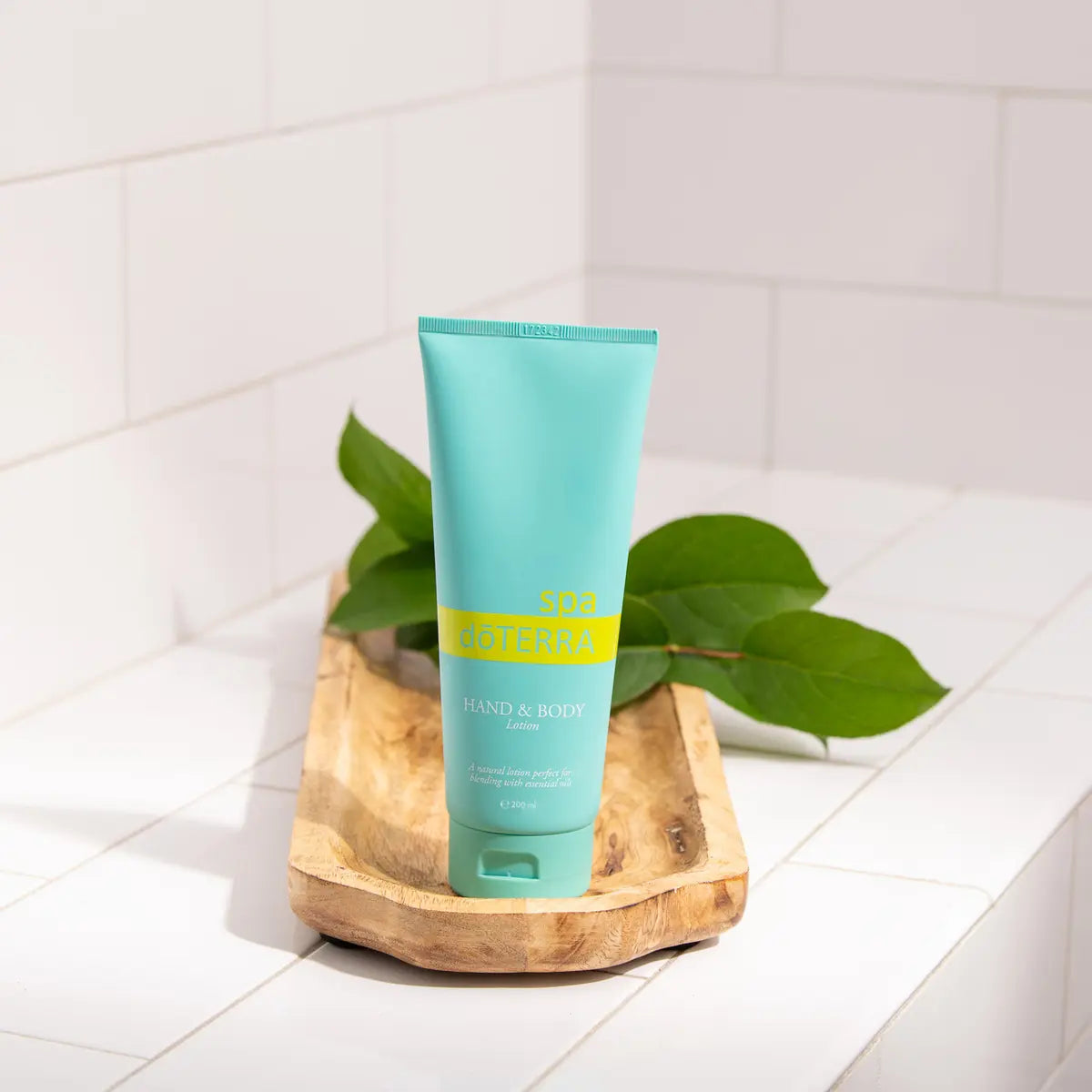 Loción Corporal y de Manos dōTERRA Spa — frasco blanco en encimera con flores