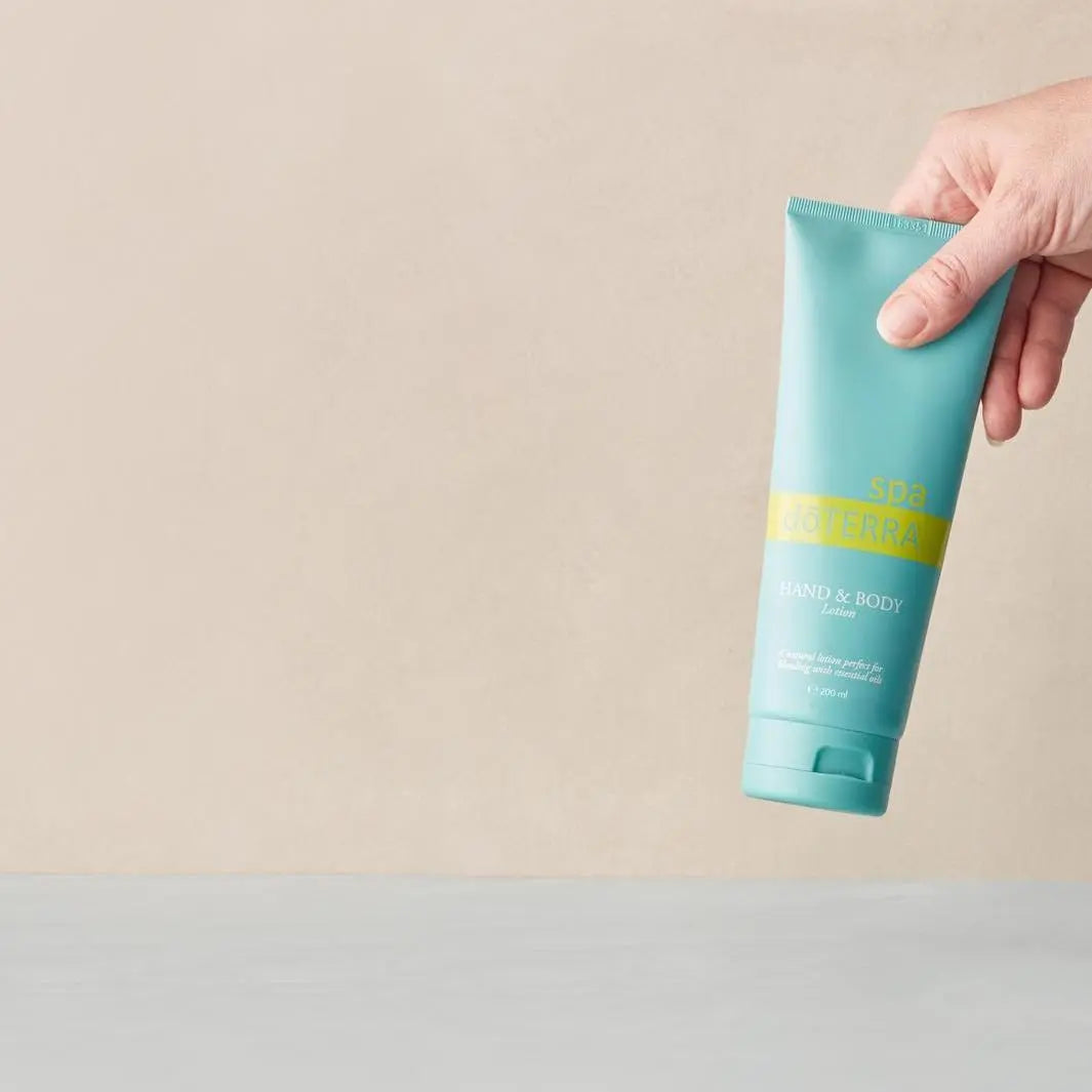 Loción Corporal y de Manos dōTERRA Spa — mano cogiendo el frasco