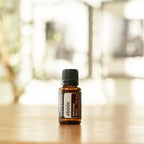 Mezcla Abode dōTERRA 15ml frasco sobre mesa de madera con decoración interior y fondo bokeh
