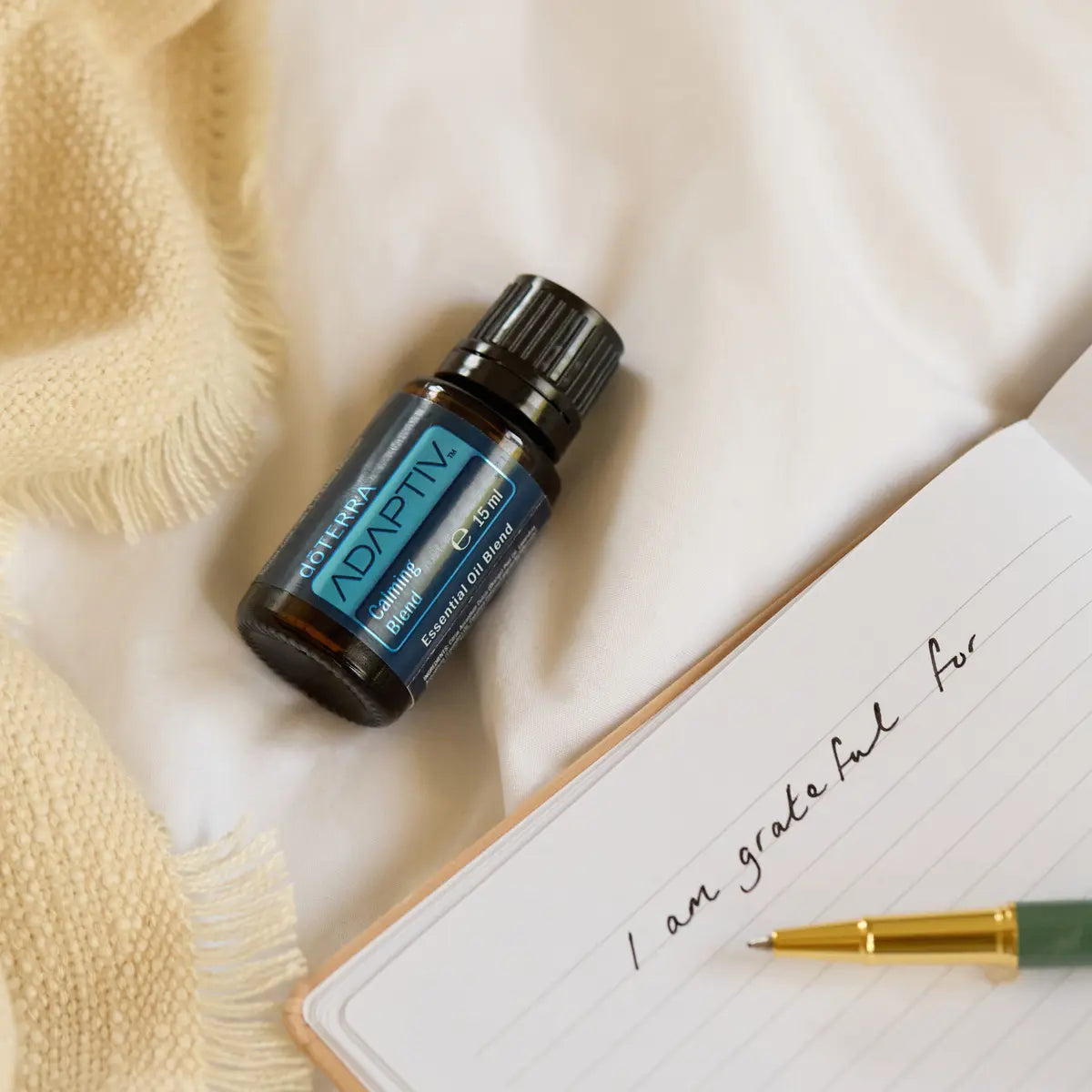 Mezcla Adaptiv dōTERRA 15ml apoyada sobre cuaderno junto a manta amarilla