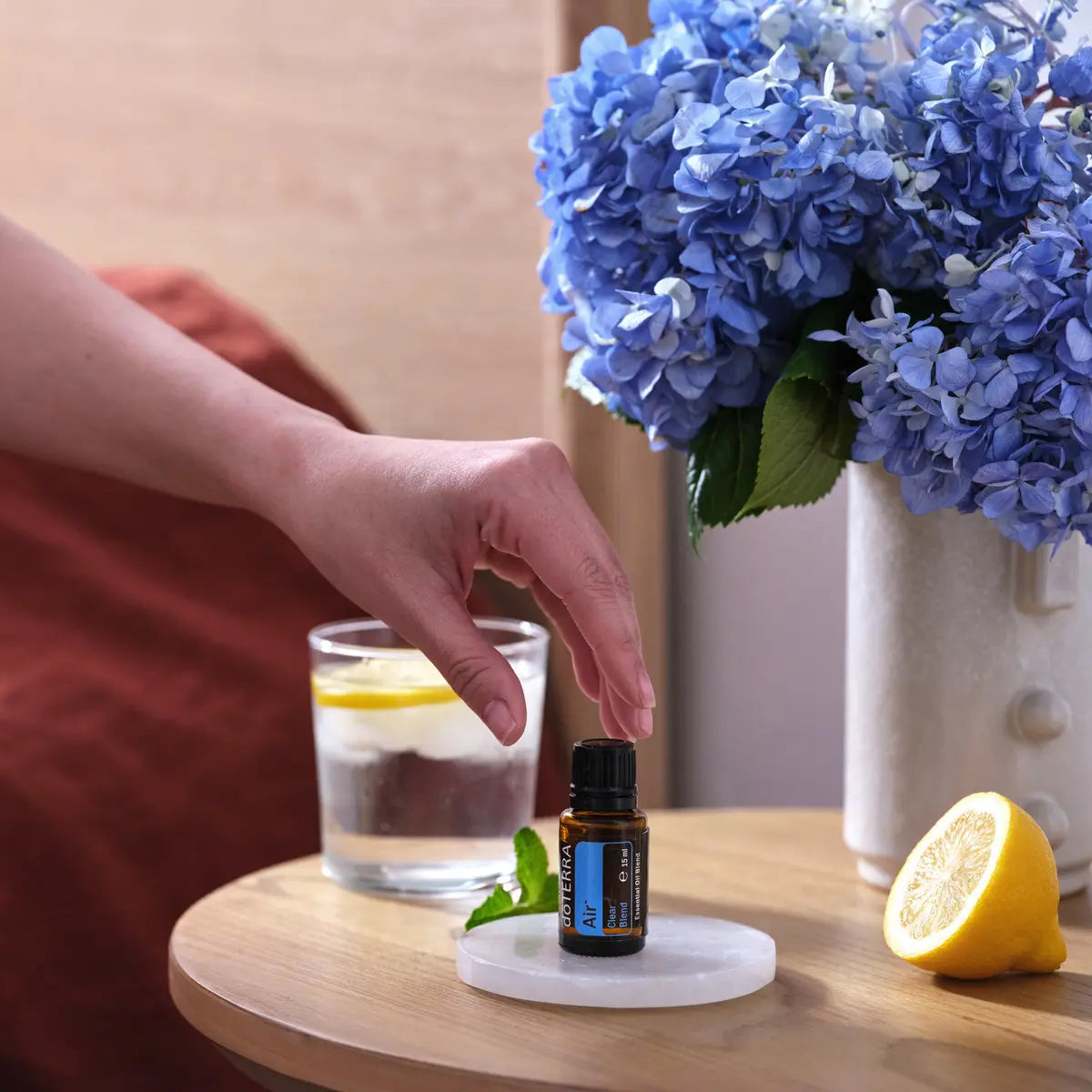 Mezcla Air dōTERRA 15ml sobre mesita de madera con hortensias azules y rodajas de limón