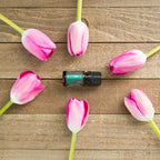 Frasco de Mezcla Align dōTERRA 5ml sobre tabla de madera rústica rodeado de tulipanes rosas, cenital