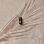 Mezcla dōTERRA Arise 5ml — frasco sobre hormigón con sombra de hoja de palma, vista cenital