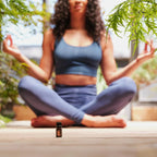Mezcla dōTERRA Arise 5ml — mujer meditando en esterilla de yoga al exterior con bokeh verde