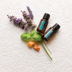 Mezcla dōTERRA AromaTouch 15ml — dos frascos con lavanda, albahaca y naranja sobre superficie rugosa